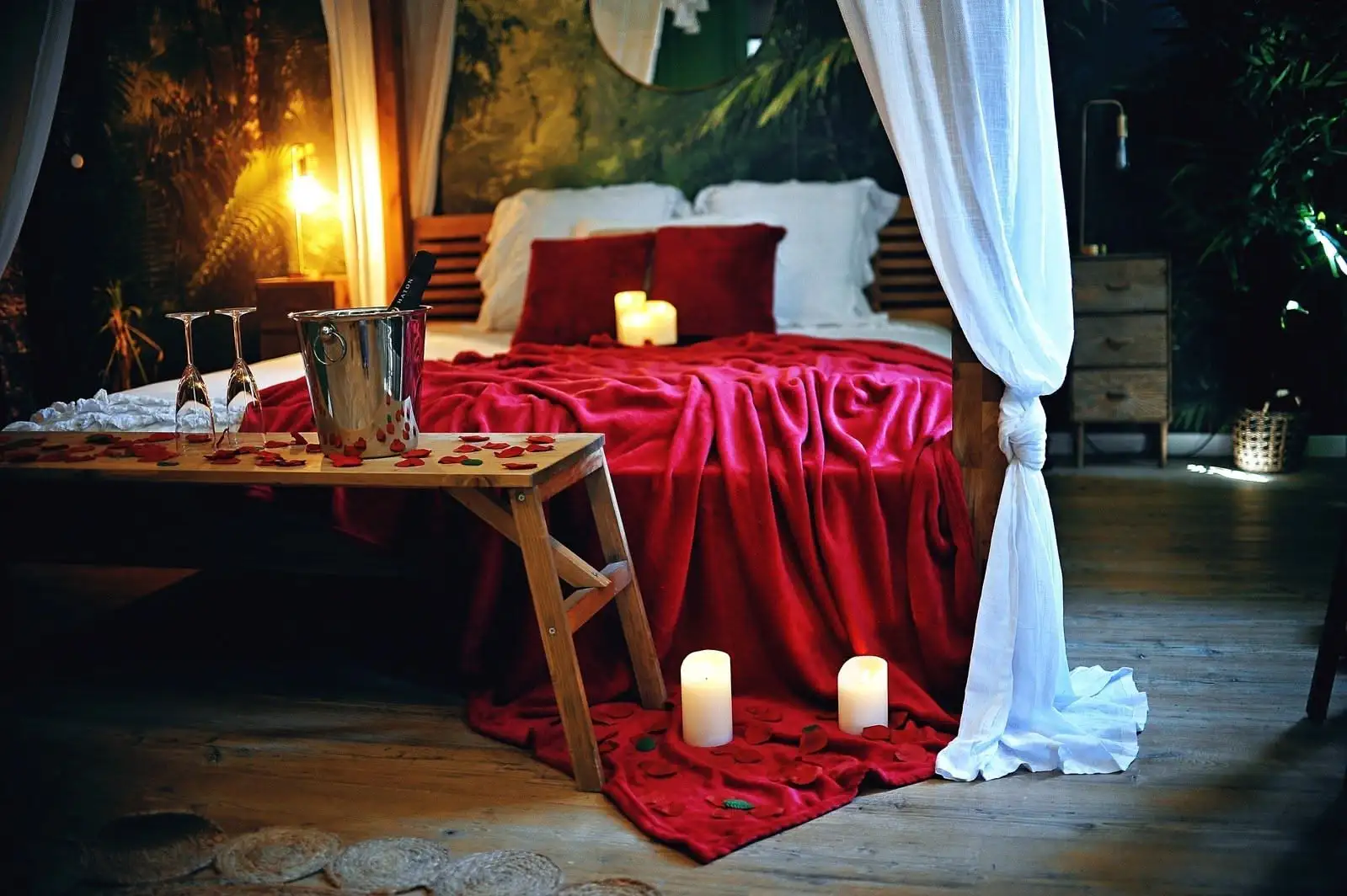 Love room romantique à thème jungle avec lit king size, lit à baldaquin, papier peint exotique, écran géant, jacuzzi, plantes, décoration sur-mesure, réservation Airbnb et Booking.