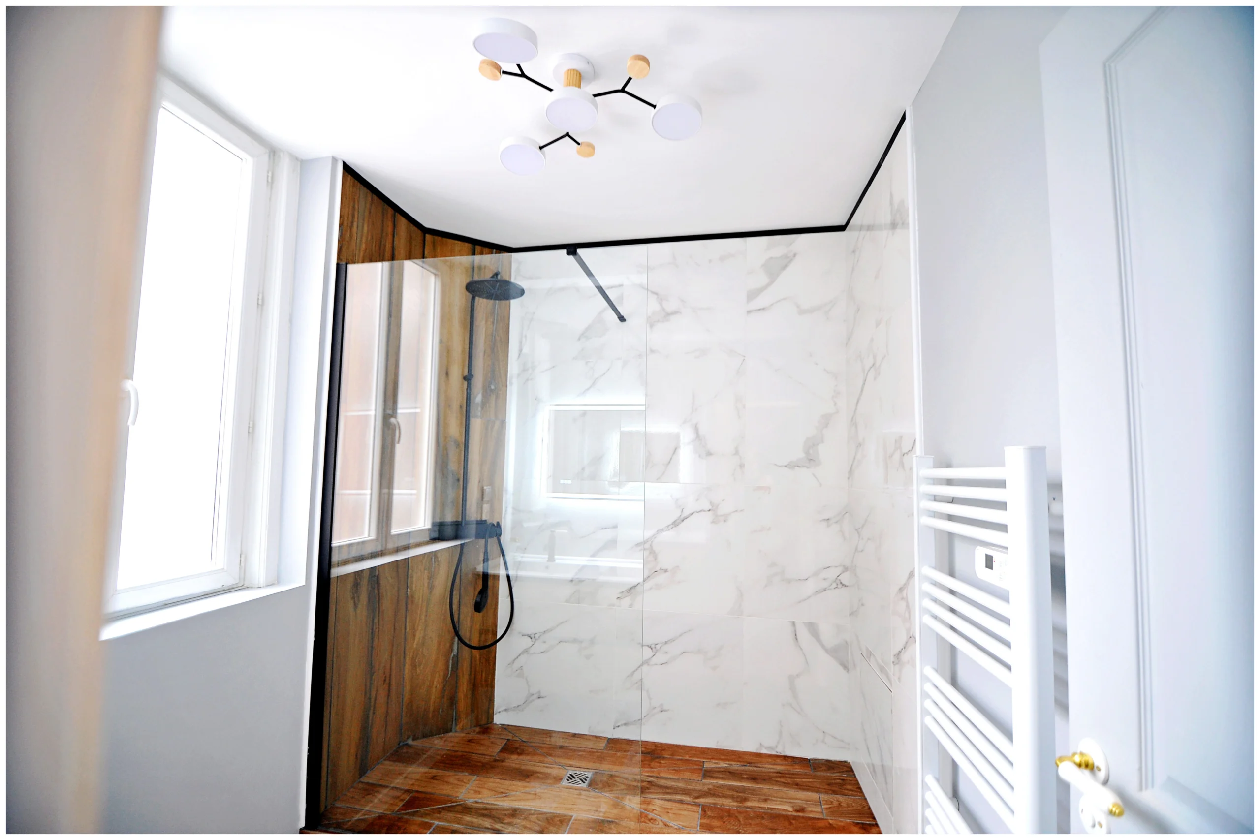 Salle de bain rénovée en colocation, élégante et fonctionnelle, avec douche moderne, meuble vasque et miroir lumineux, ambiance lumineuse et raffinée.