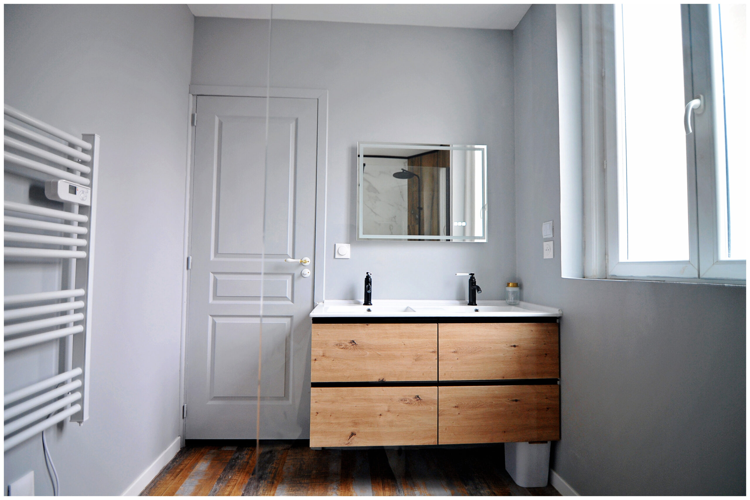 Salle de bain rénovée en colocation, élégante et fonctionnelle, avec douche moderne, meuble vasque et miroir lumineux, ambiance lumineuse et raffinée.