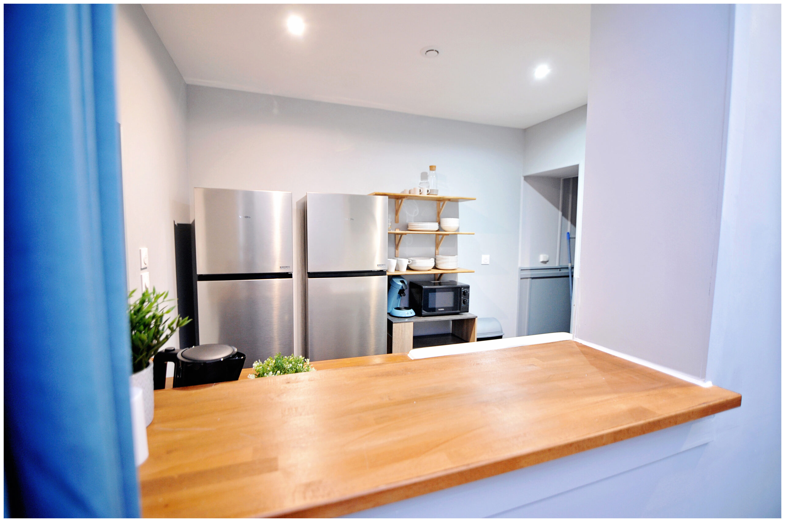 Cuisine rénovée en colocation, fonctionnelle et moderne, avec deux frigos, lave-vaisselle et crédence en carreaux de ciment, idéale pour six colocataires.
