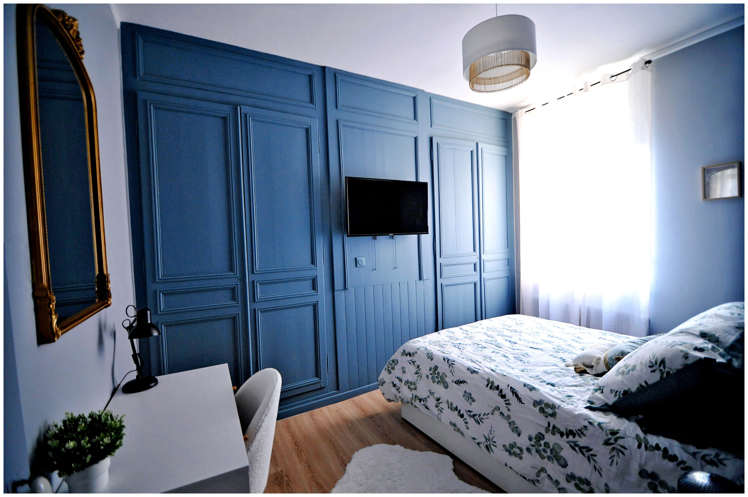 Chambre rénovée en colocation avec un lit coffre pratique, une décoration chaleureuse aux tons bleu et gris, une tête de lit en osier et une ambiance cosy et apaisante.